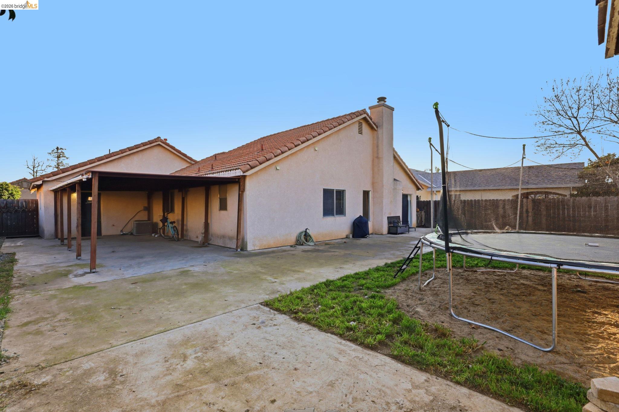 799 Morgans Ranch Circle Galt, CA 95632 - Photo 34 of 36 View of side of home with a fenced backyard, a trampoline, stucco siding, and a chimney