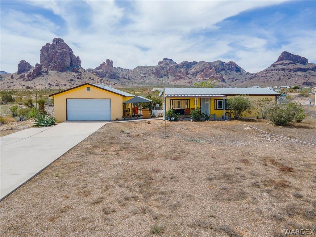 2465 Egar Road Golden Valley, AZ 86413 - Photo 66 of 98 The property features a yellow exterior and a concrete driveway leading to a garage