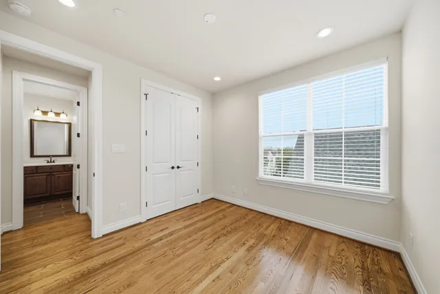 a view of empty room with wooden floor and a window