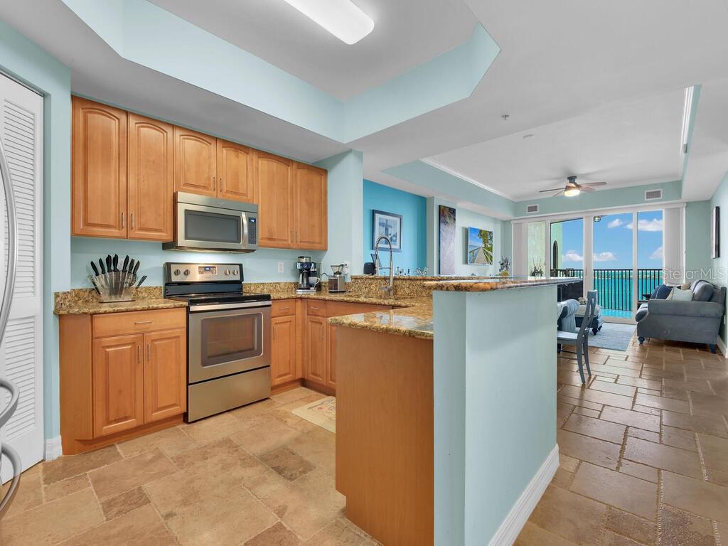 2797 First Street, Unit 1605 Fort Myers, FL 33916 - Photo 9 of 38 a kitchen with granite countertop a stove top oven a sink dishwasher a dining table and chairs with wooden floor