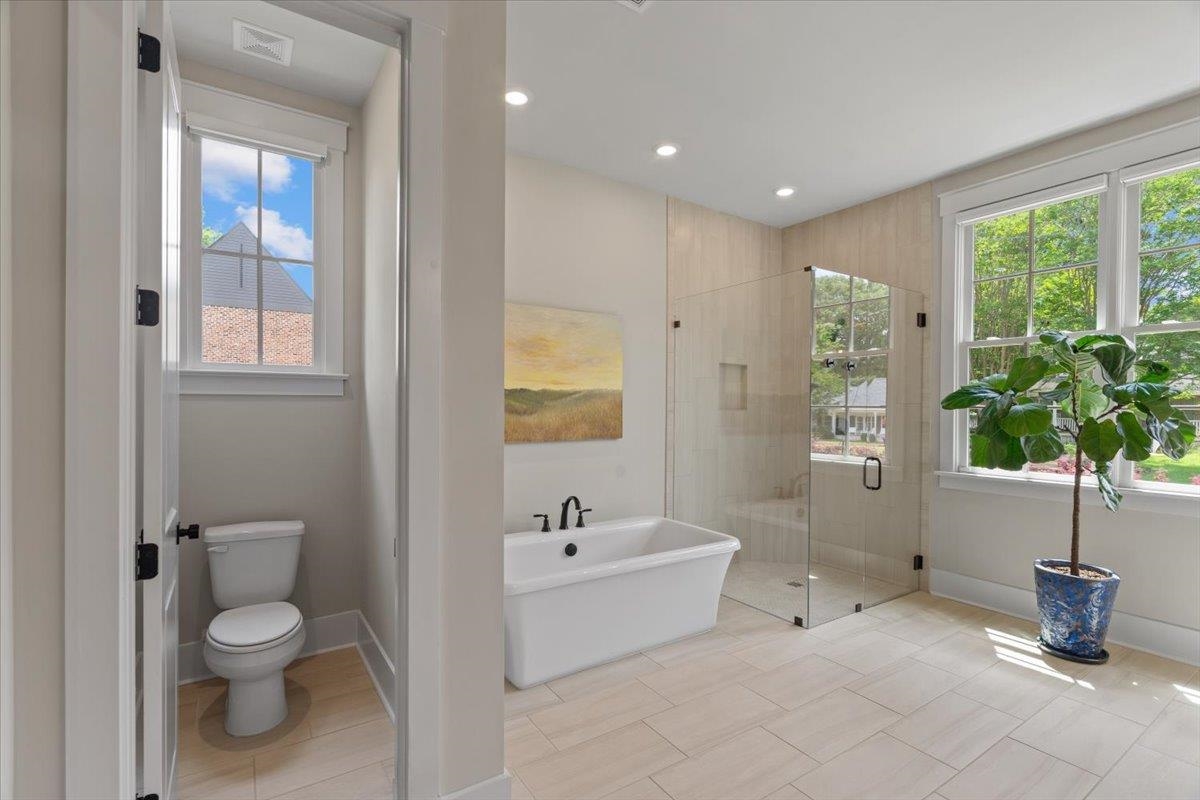 240 Burrows Road Collierville, TN 38017 - Photo 15 of 37 Spacious bathroom featuring light-toned tile flooring, a freestanding soaking tub with matte black fixtures, and a glass-enclosed shower with a tiled bench and niche