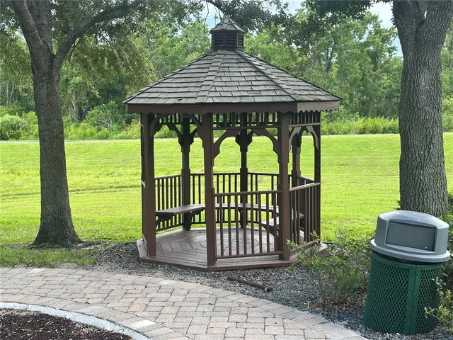 a view of a patio with a table and chairs under an umbrella with large trees