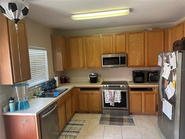 a kitchen with stainless steel appliances a stove a sink cabinets and a window