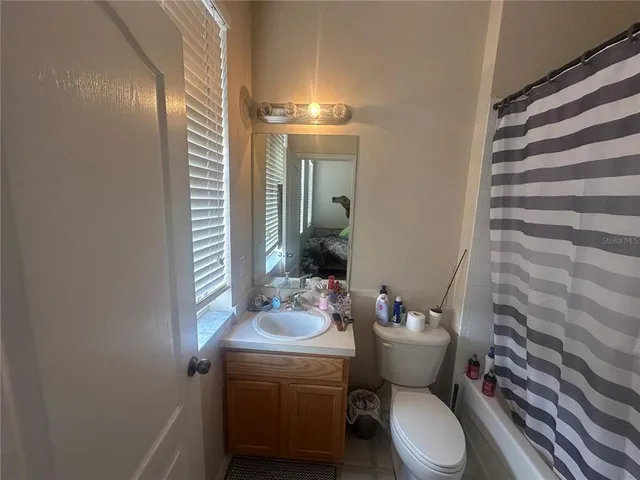 a bathroom with a sink a toilet a mirror and shower curtain