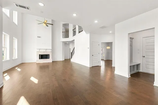 a view of an empty room with wooden floor and a kitchen