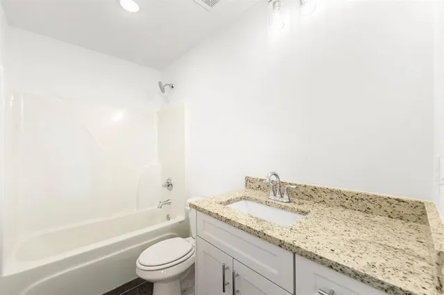 a bathroom with a granite countertop sink a toilet and bathtub