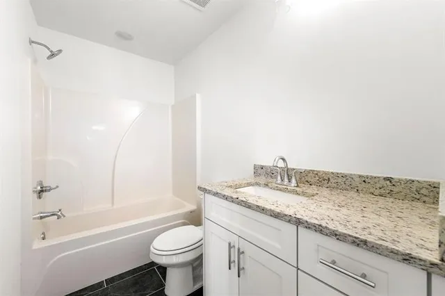 a bathroom with a granite countertop sink a toilet and shower