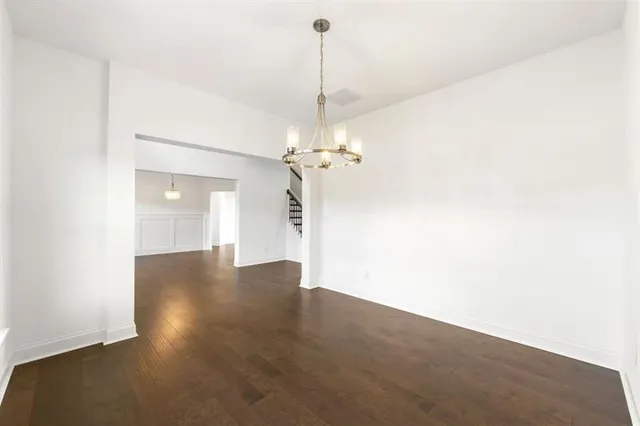 a view of a room with a chandelier fan and wooden floor