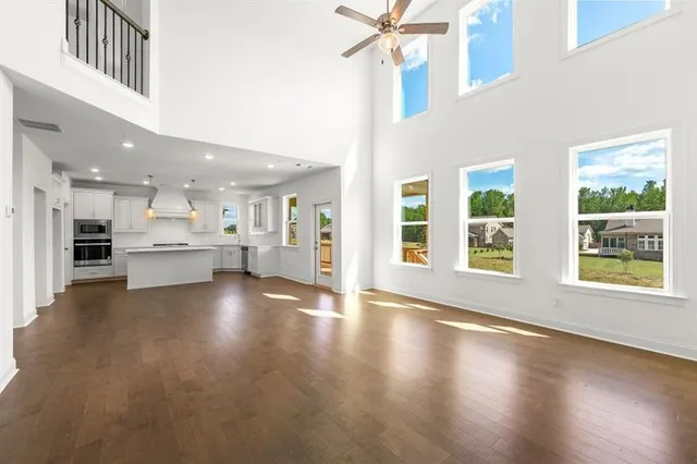 a view of an empty room with wooden floor and a kitchen