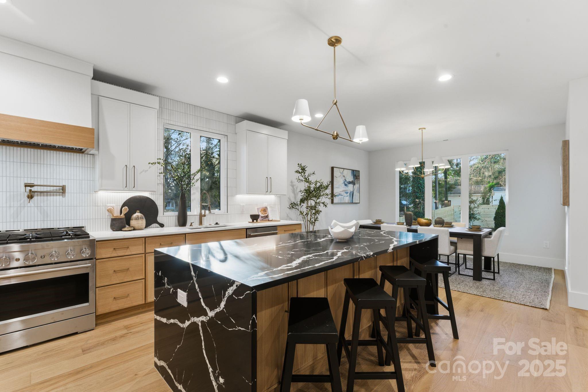 4658 Murrayhill Road Charlotte, NC 28209 - Photo 11 of 48 a kitchen with stainless steel appliances granite countertop a stove top oven a sink a dining table and chairs with wooden floor