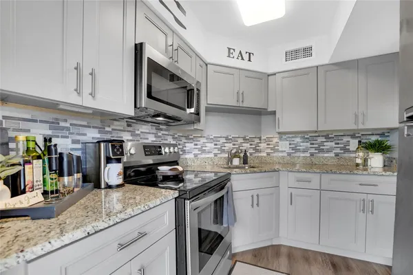 a kitchen with granite countertop a sink a stove and cabinets