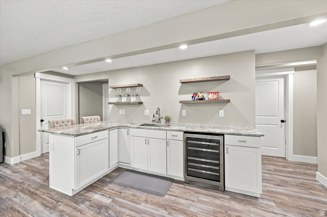 615 West 1870th Street South Payson, UT 84651 - Photo 15 of 31 L-shaped wet bar featuring white cabinetry, light-toned countertops, a stainless steel beverage refrigerator, and wood-finish open shelving