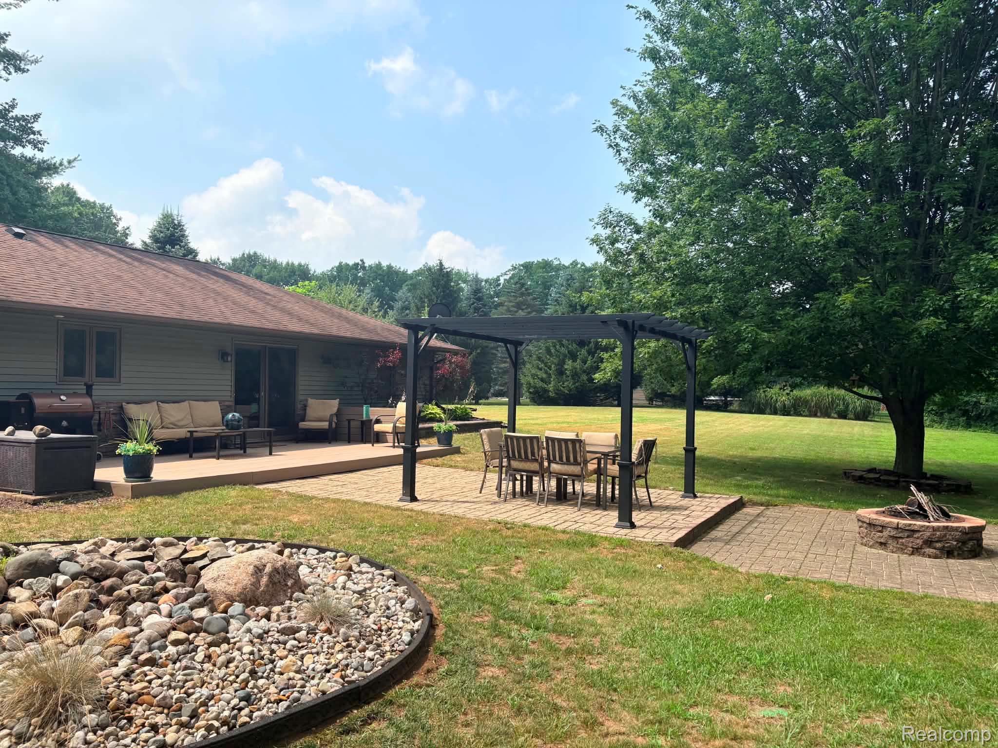 2159 East Bevens Road Caro, MI 48723 - Photo 7 of 38 Expansive backyard featuring a paver patio with a pergola, a stone fire pit, koi pond, and mature trees surrounding a large lawn area