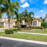 a front view of a house with a yard and palm trees