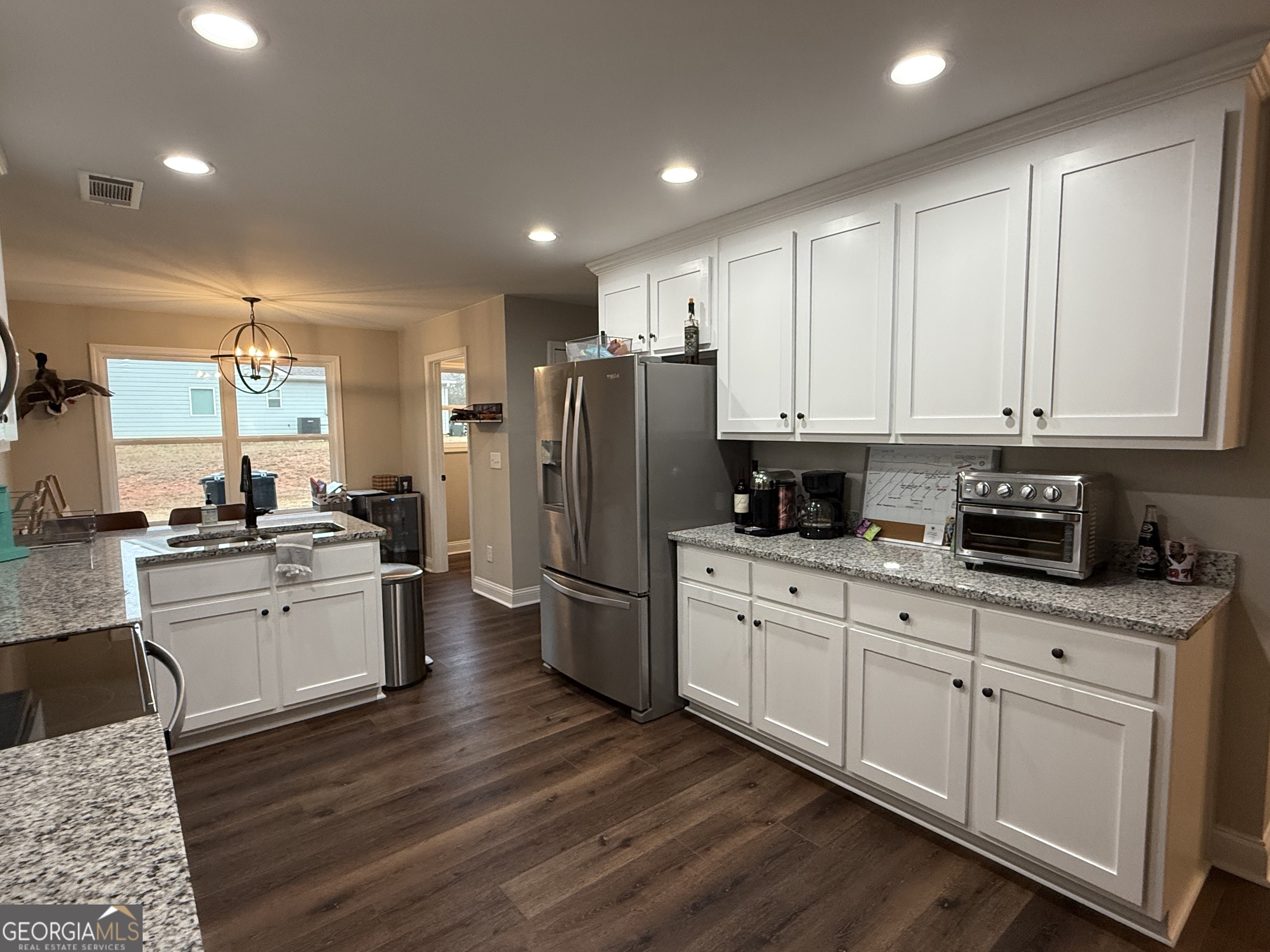 712 Scott Mill Road Hartwell, GA 30643 - Photo 12 of 31 a kitchen with a refrigerator a sink dishwasher a stove and white cabinets with wooden floor