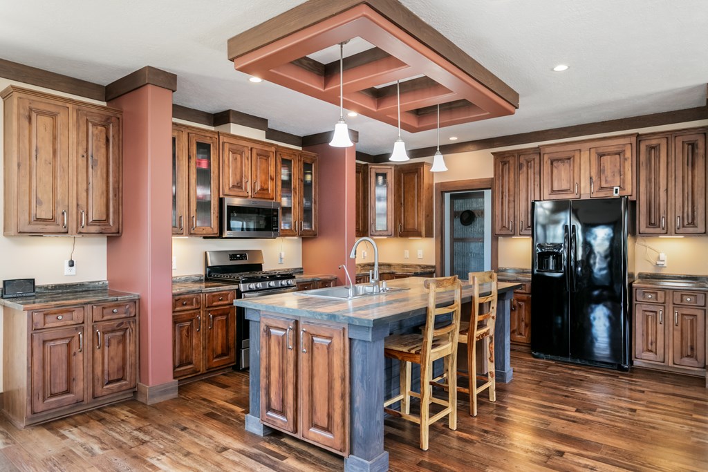 134 Concho Trail Harper, TX 78631 - Photo 11 of 31 a kitchen with stainless steel appliances granite countertop a stove top oven a refrigerator a sink and dishwasher with wooden floor