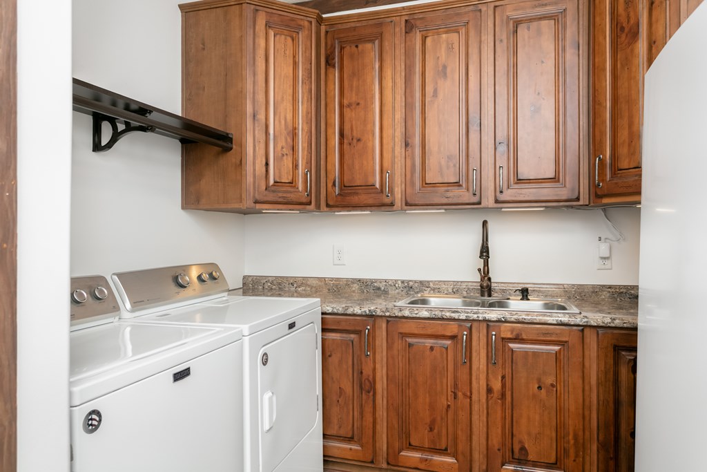 134 Concho Trail Harper, TX 78631 - Photo 18 of 31 a utility room with granite countertop a sink a washer and dryer with wooden cabinets