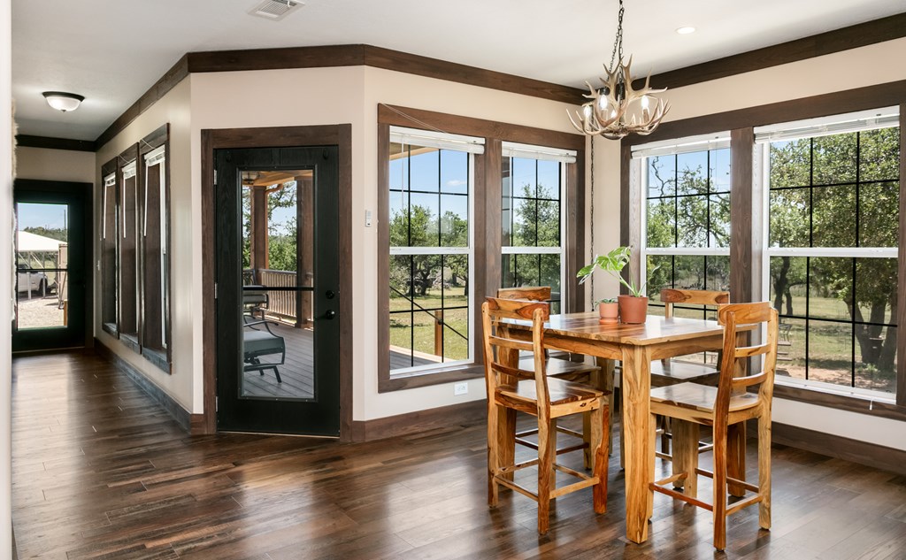 134 Concho Trail Harper, TX 78631 - Photo 10 of 31 a dining room with wooden floor a chandelier a glass table and chairs