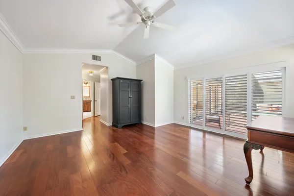 an empty room with wooden floor fan and windows