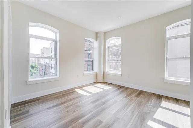 a view of an empty room with wooden floor and a window
