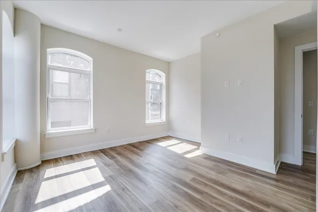 an empty room with wooden floor and windows