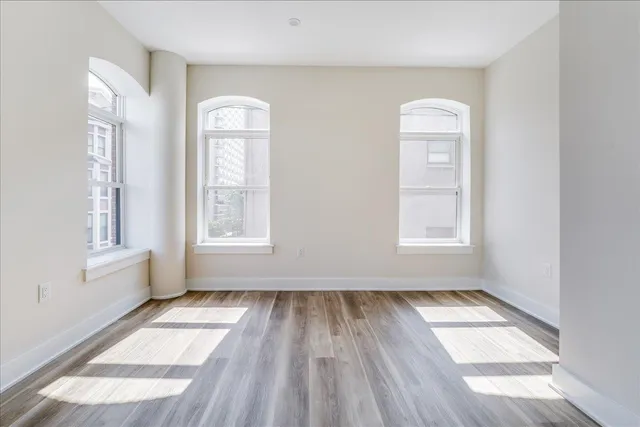 an empty room with wooden floor and windows