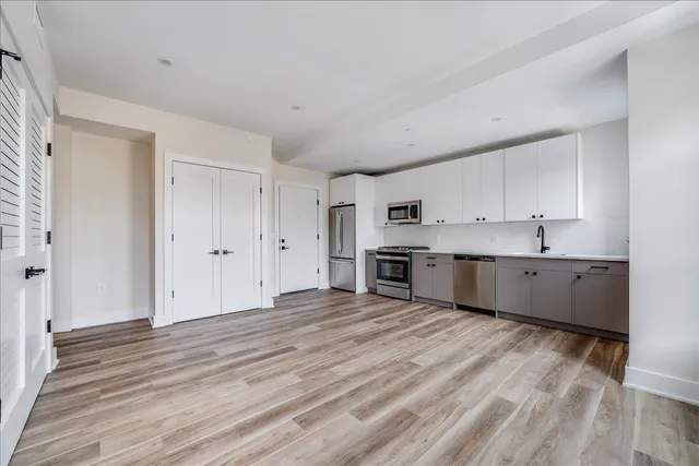 a large white kitchen with kitchen island a sink stainless steel appliances and cabinets