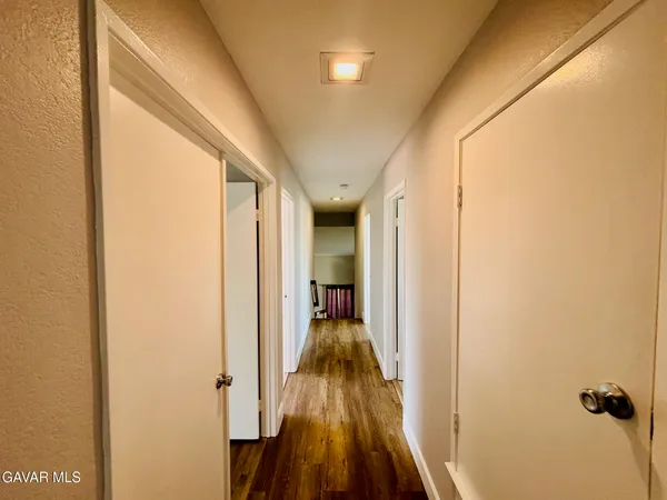 a view of a hallway with wooden floor and a living room