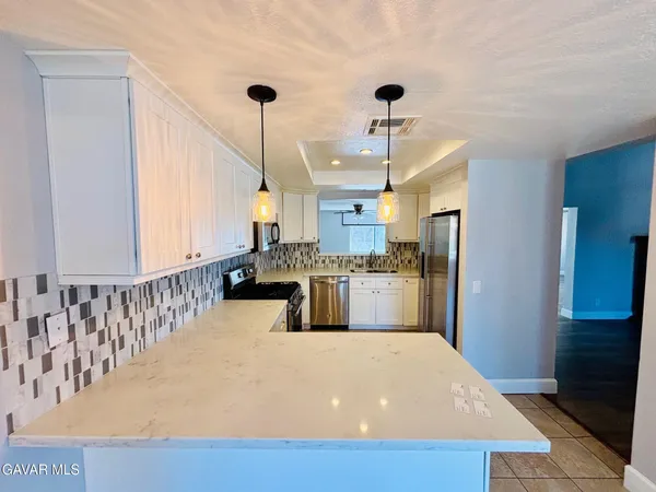 a kitchen with stainless steel appliances kitchen island a white counter space a sink and a window