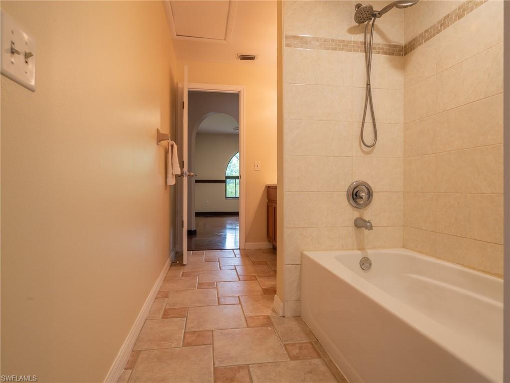 18414 Tulip Road Fort Myers, FL 33967 - Photo 26 of 37 Bathtub and shower combination featuring a tiled surround with decorative accent band