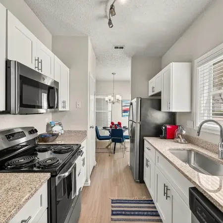 a kitchen that has a lot of cabinets a sink and appliances