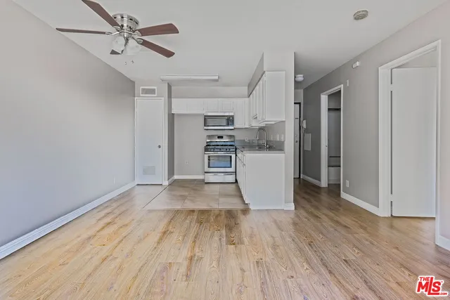 a view of a kitchen with wooden floor a sink and stainless steel appliances