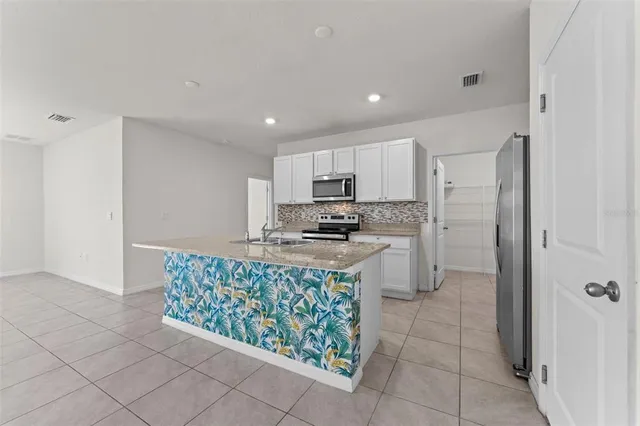 a kitchen with stainless steel appliances granite countertop a refrigerator and a stove top oven
