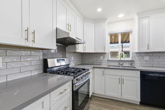 a kitchen with granite countertop a sink a stove and cabinets
