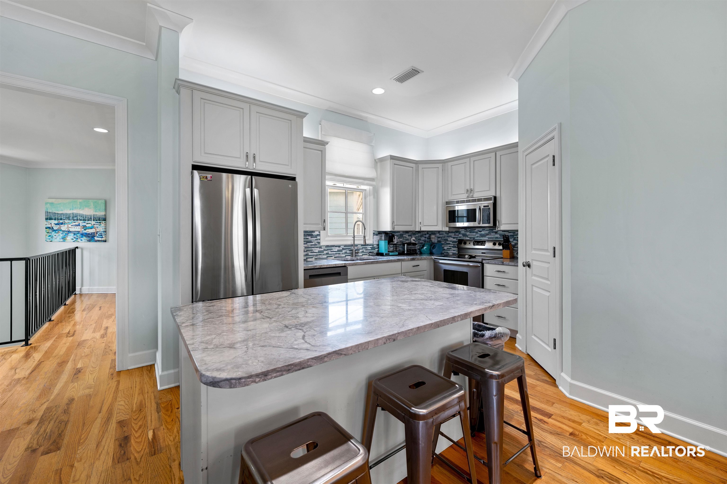 3434 Mariner Circle Orange Beach, AL 36561 - Photo 18 of 38 Kitchen featuring appliances with stainless steel finishes, light hardwood / wood-style flooring, a breakfast bar, decorative backsplash, and crown molding. All new appliances and cabinets.