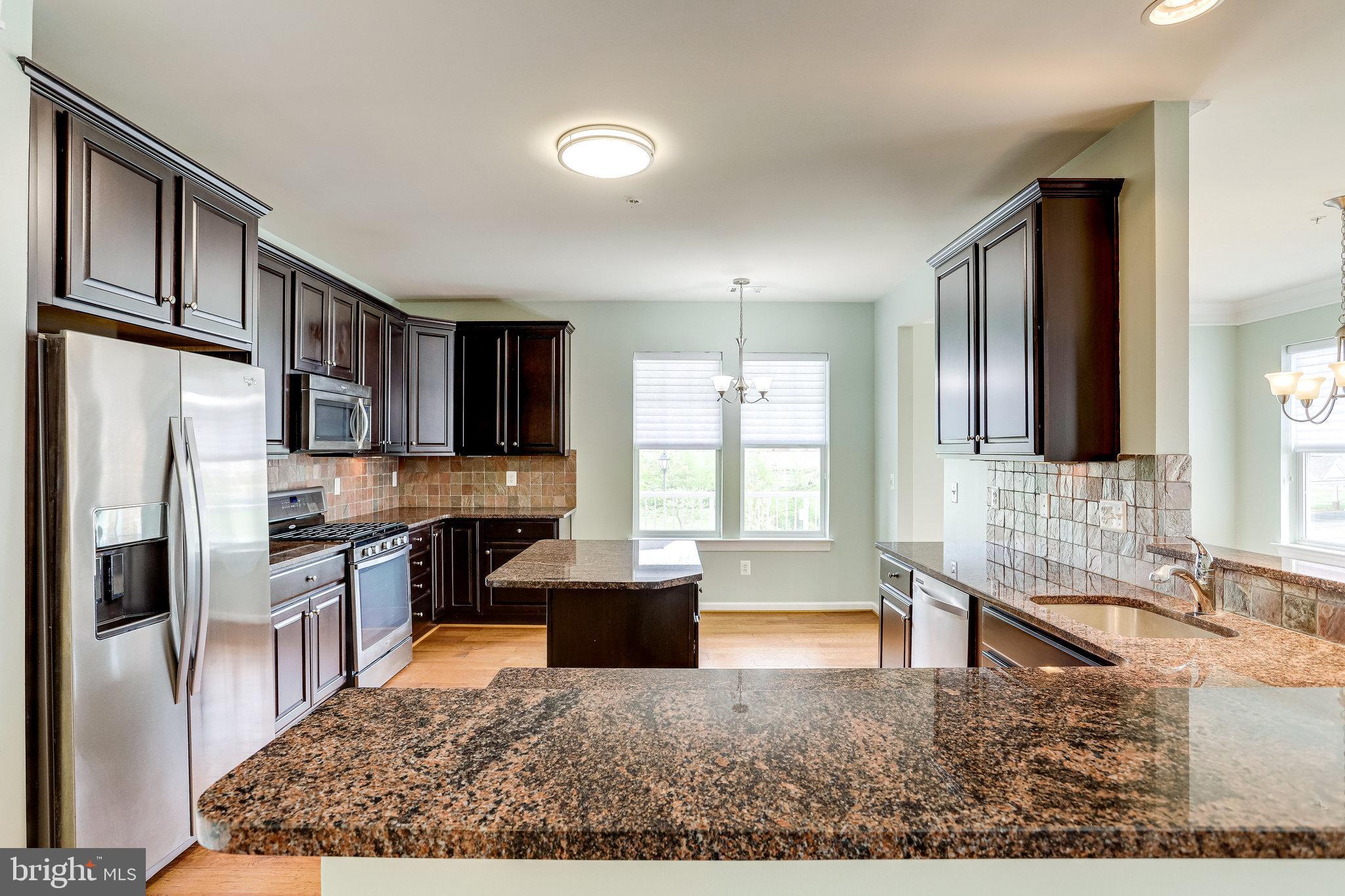 20580 Hope Spring Terrace, Unit 207 Ashburn, VA 20147 - Photo 18 of 61 a kitchen with stainless steel appliances granite countertop a refrigerator stove microwave and sink
