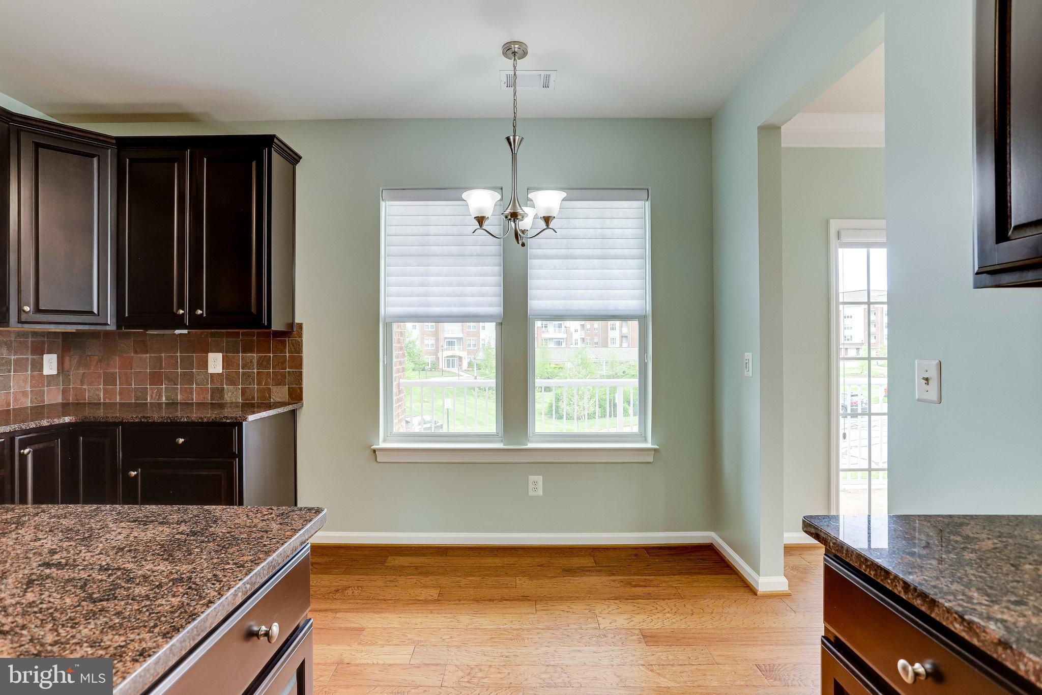 20580 Hope Spring Terrace, Unit 207 Ashburn, VA 20147 - Photo 19 of 61 a kitchen with granite countertop wooden cabinets a sink dishwasher and a stove with wooden floor