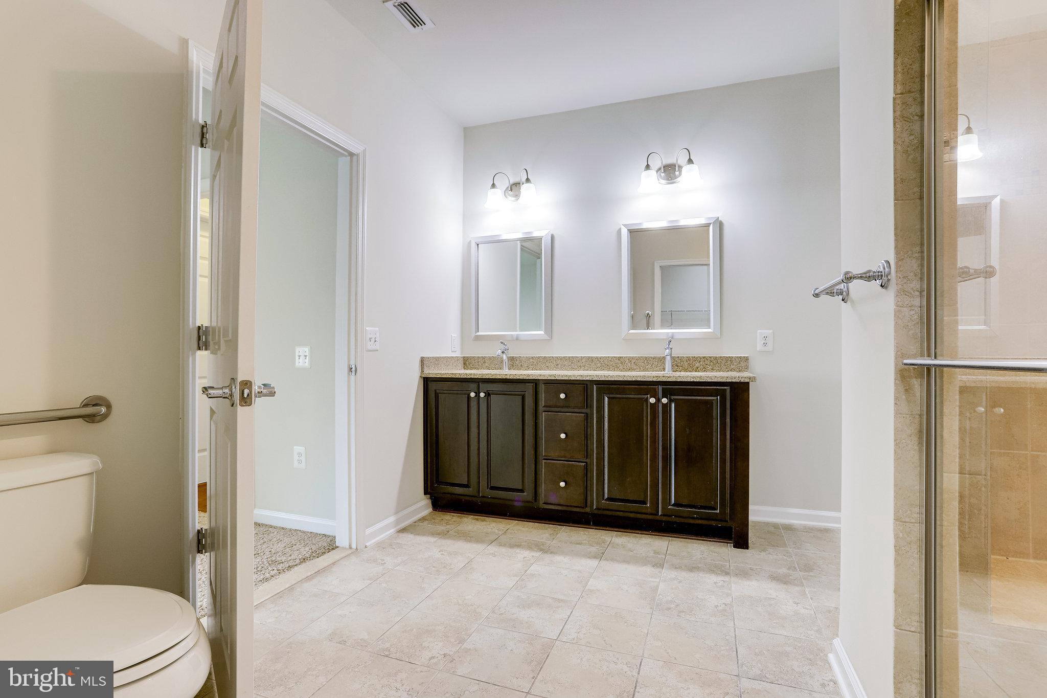 20580 Hope Spring Terrace, Unit 207 Ashburn, VA 20147 - Photo 22 of 61 a spacious bathroom with a granite countertop sink a toilet mirror and a vanity