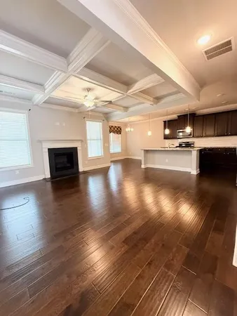 an empty room with wooden floor chandelier and windows