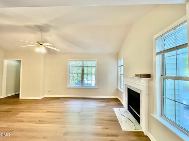 a view of a livingroom with wooden floor a fireplace and windows