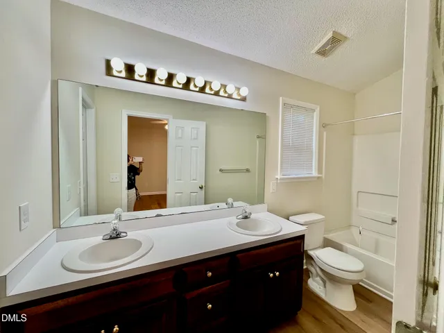 a bathroom with a double vanity sink toilet and a mirror