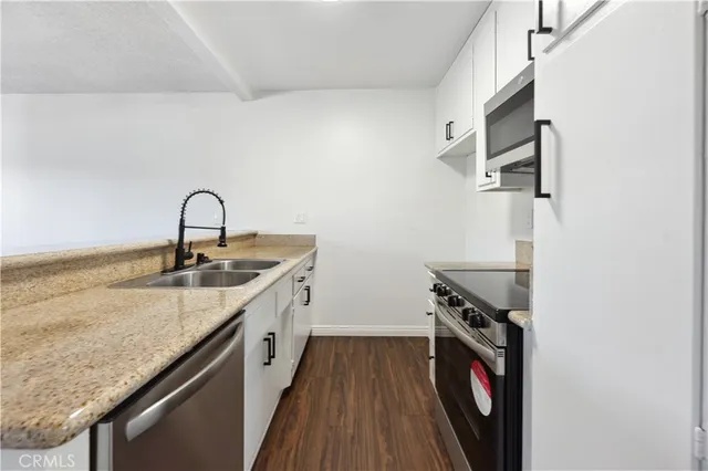 a hallway with granite countertop a sink and a stove with wooden floor