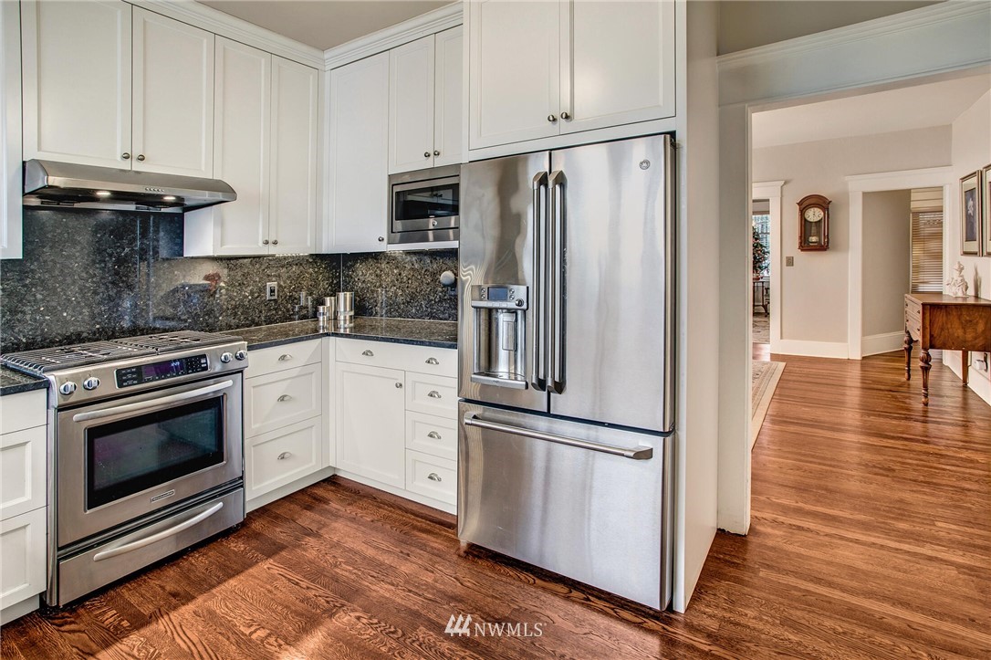 1415 East Spring Street Seattle, WA 98122 - Photo 11 of 38 a kitchen with granite countertop a refrigerator stove and white cabinets