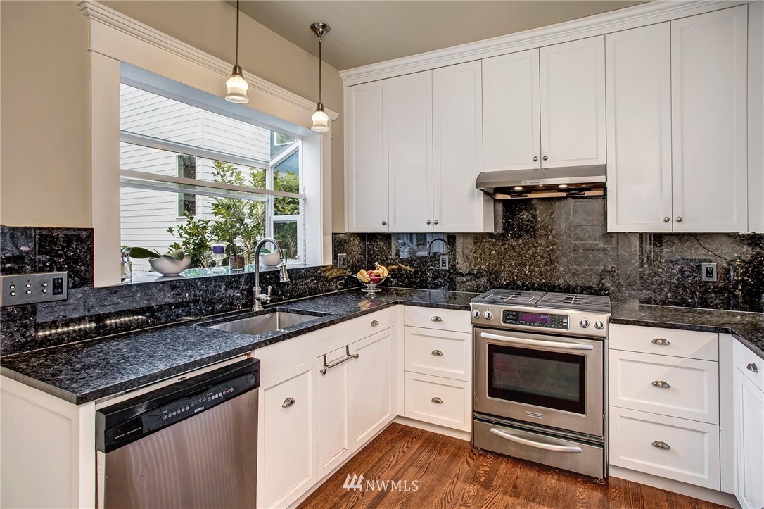 1415 East Spring Street Seattle, WA 98122 - Photo 10 of 38 a kitchen with granite countertop white cabinets and white appliances