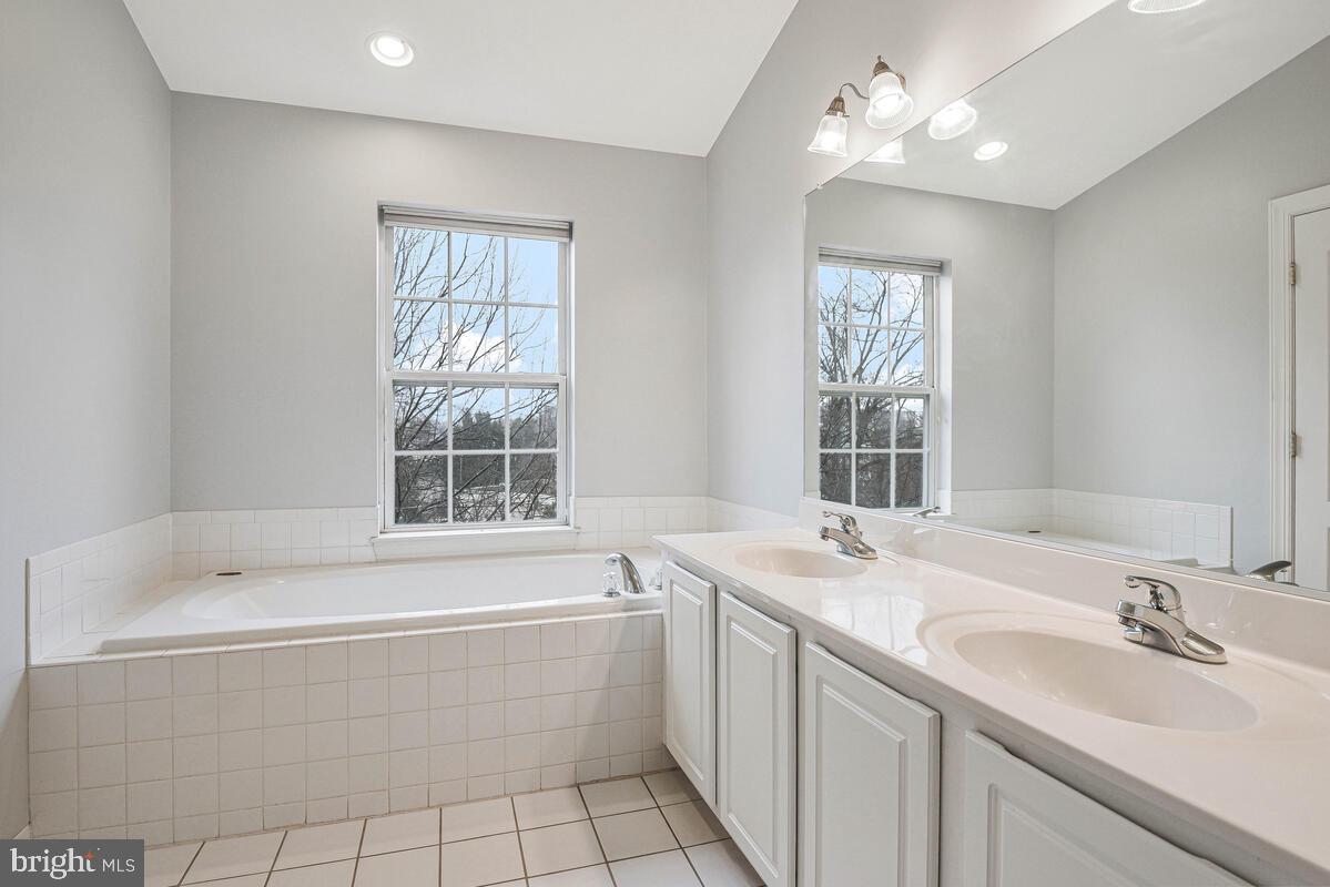 8045 Gatehouse Road, Unit 17 Falls Church, VA 22042 - Photo 26 of 32 a bathroom with a sink a bathtub a mirror a vanity a window and a shower