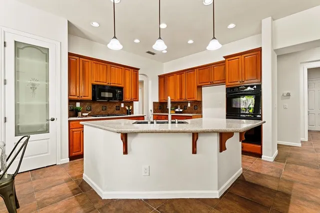 a kitchen with stainless steel appliances granite countertop a sink a stove and a refrigerator