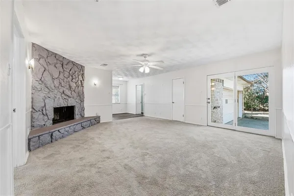 an empty room with windows and fireplace
