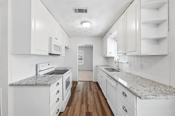 a kitchen with granite countertop a sink stove and cabinets