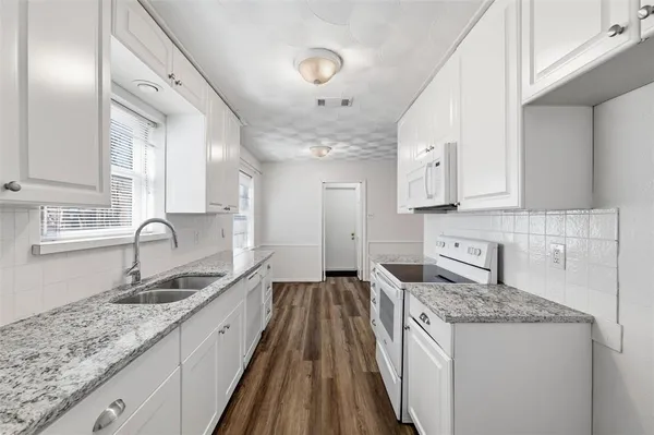 a kitchen with granite countertop a sink stove and cabinets