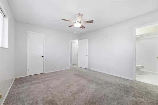 an empty room with closet and a ceiling fan